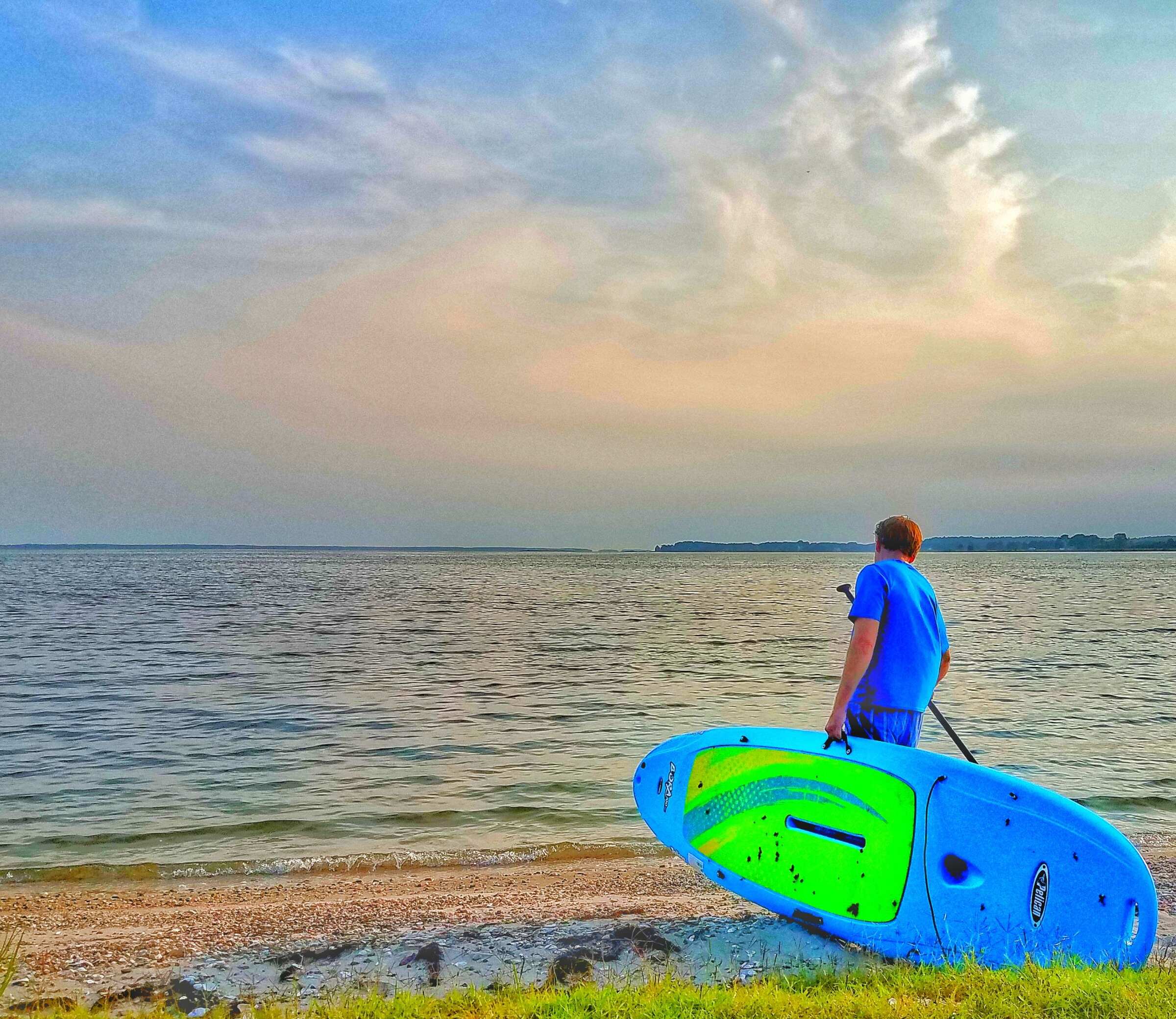 A young man brings a paddleboard to the Chesapeake Bay