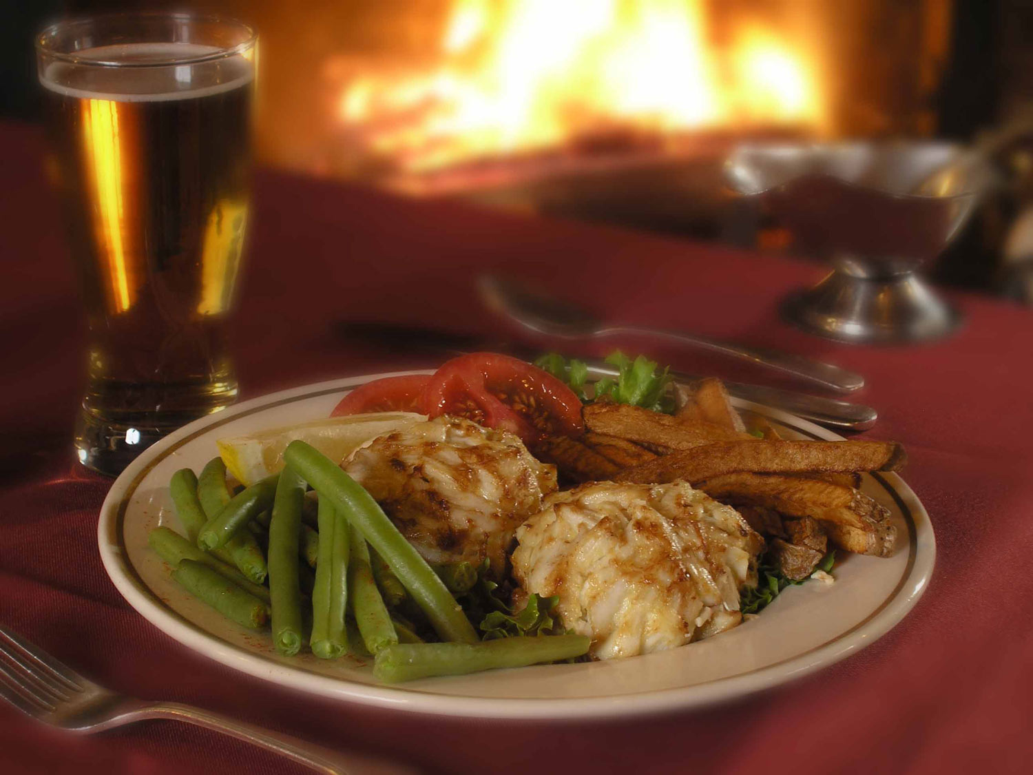 Two crab cakes on a platter by fireside dining